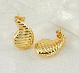Gros plan de boucles d'oreilles en acier inoxydable doré 18 carats avec texture striée
