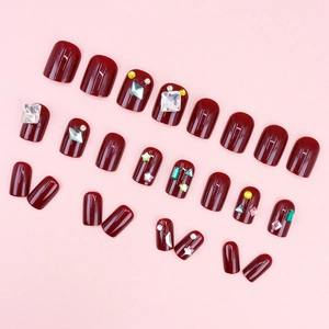 Glossy burgundy red press-on nails set with luxury rhinestone accents and silver gems