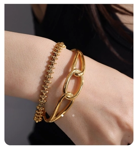 Close-up of golden chain link bracelet and geometric spike bangle on a wrist
