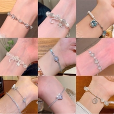 Close-up of nine vintage titanium steel bracelets with pearl and star charms