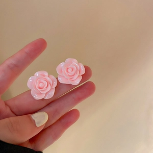 Gros plan de boucles d'oreilles roses en forme de fleur tenues à la main en résine