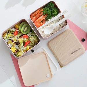 Close-up of pink double-layer bento box with wooden style lid and reusable cutlery set