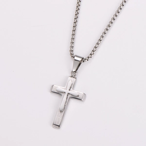 Macro shot of silver stainless steel cross pendant with textured pattern on box chain