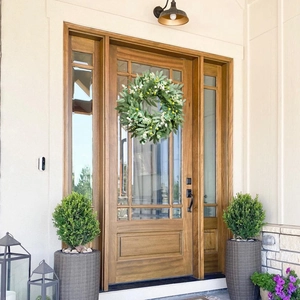 Artificial olive leaf and white berry wreath hanging on a brown wooden front door