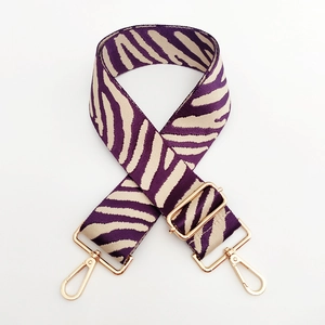 Detail of adjustable purple zebra pattern strap with gold metal hooks for handbags