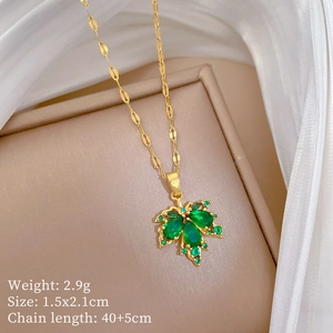Macro view of gold maple leaf pendant with green gemstones and elegant chain detail