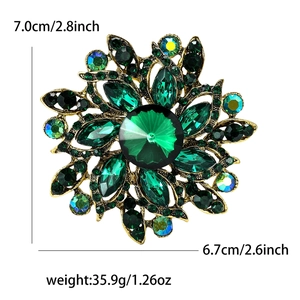 Elegant vintage flower brooch with green rhinestones and crystals on golden base