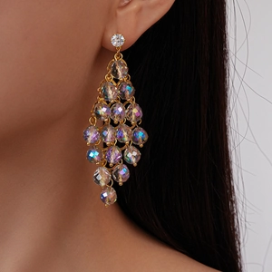 Close-up of dangling diamond rhombic crystal earrings with gold tassel fringe on model