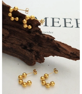 Detailed view of 18k gold plated titanium steel C-shaped earrings with round bead design