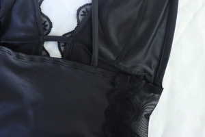 Detail of black satin dress featuring delicate lace trim and mesh inserts on white fabric