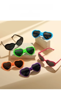 Macro display of six colorful heart-shaped sunglasses on stone pedestals in soft sunlight