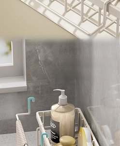 Detail of a cream metal kitchen sink rack featuring a detachable rod for hanging dishcloths