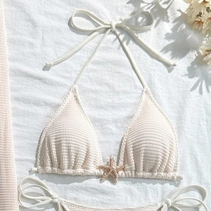 Detailed close-up of white crochet bikini top with elegant metal starfish ornament detail
