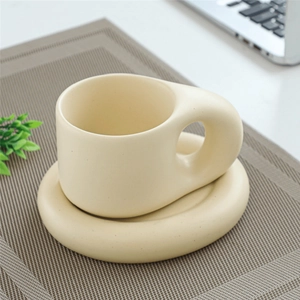 Close-up of a beige ceramic fat-handle mug and saucer on a woven mat for breakfast