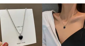 Close-up of heart-shaped black enamel pendant with silver ball chain on female model