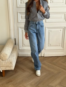 Damen Vintage Schlagjeans in Hellblau mit grauer Kurzjacke und weißen Turnschuhen