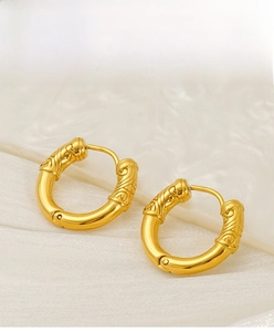 Detailed macro view of gold stainless steel hoop earrings with embossed retro patterns