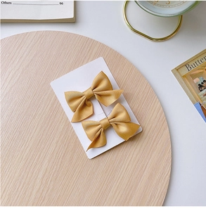 Macro shot of two satin champagne bow hair clips for girls on a wooden tray