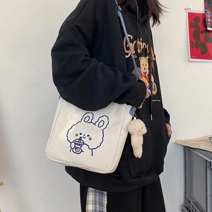 Minimalist white canvas tote bag with blue rabbit illustration and plush bear charm