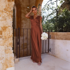 Detailed view of the rust-colored satin fabric and wrap V-neckline of the long party gown