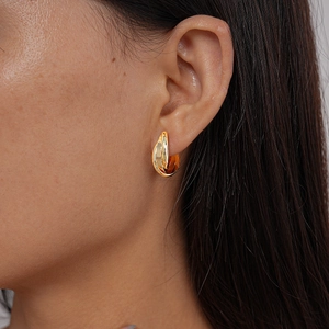 Close-up of golden multi-layer twisted clip-on earrings on female model ear