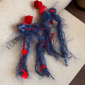 Dettaglio ravvicinato delle nappe blu scuro e rosa in velluto rosso su orecchini ad ago d'argento