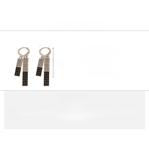Détail de boucles d'oreilles géométriques longues avec strass noirs et clairs