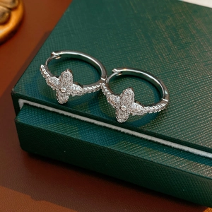Macro shot of silver clover hoop earrings with cubic zirconia on a green leather box