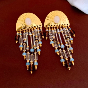 Détail des boucles d'oreilles éventail vintage dorées avec pompons en perles colorées