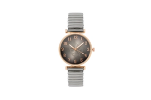 Detail of rose gold watch bezel with grey dial featuring palm leaf motif and elastic band