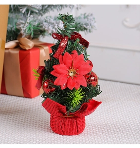 Close-up of mini Christmas tree with red flowers, bows and gold ornaments for desk decor
