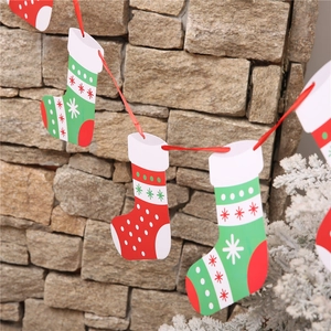 Detail of Christmas stocking paper banners hanging on a red ribbon against a stone wall