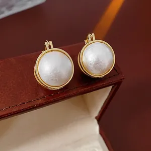 Boucles d'oreilles perles vintage à levier dorées posées sur un écrin en cuir
