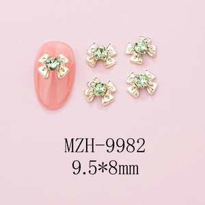 Macro view of gold bow-knot nail charm with green heart gemstone, 9.5x8mm size detail