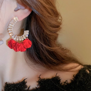 Détail de grandes boucles d'oreilles en C avec pétales rouges et zircons sur modèle