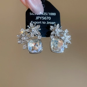 Détail macro de boucles d'oreilles fleur en argent 925 avec un grand zircon carré