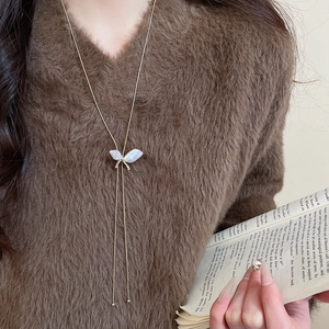 Detail of a butterfly pendant necklace with pearls and zircon on a brown sweater