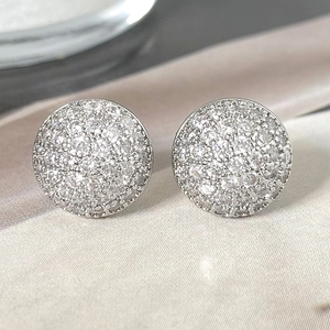 Macro view of silver round stud earrings with micro-pave cubic zirconia on satin