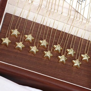 Star shaped gold letter pendants A to L with micro-pave cubic zirconia on wood display