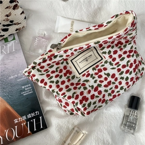 Close-up of pleated cherry print cosmetic bag with Pleasant Time label and zipper