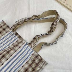 Detail of vintage patchwork canvas tote bag with ruffles and frayed edges on white fabric
