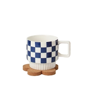 Ceramic checkered coffee mug with square handle on a flower cork coaster in studio light