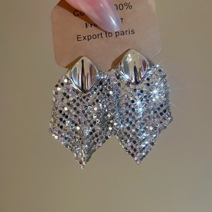 Close-up of sparkling silver rhombic studs with long sequin mesh fringe dangles