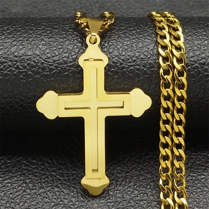 Vue macro du pendentif double croix dorée sur chaîne cubaine sur fond en cuir noir