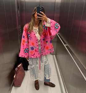 Detailed pink bohemian cardigan featuring vibrant floral embroidery and loose-fit sleeves