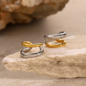 Minimalist twisted gold and silver ear cuffs set displayed on a natural stone surface