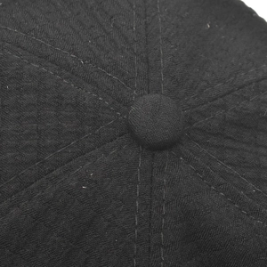 Vista macro di un cappello nero a nido d'ape con bottone superiore e cuciture rinforzate