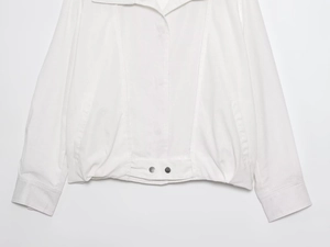 Detail of white bomber jacket showing fabric texture and silver metal hem buckle