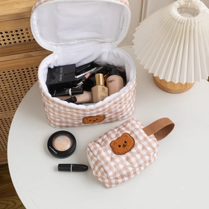 Detail of checkered quilted cosmetic bag set featuring a cute brown teddy bear patch
