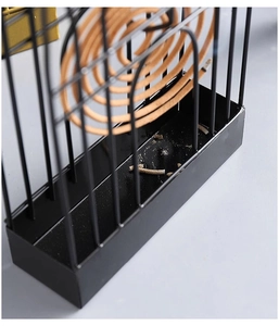 Macro view of black birdcage mosquito coil holder with incense burning inside the metal cage